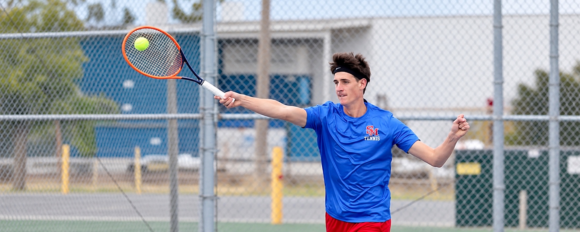 Tennis player reaching to return a ball on court.